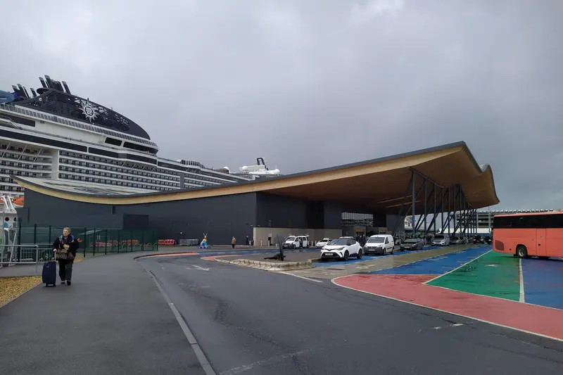 The wave-shaped roof of Horizon Cruise Terminal with an MSC ship alongside